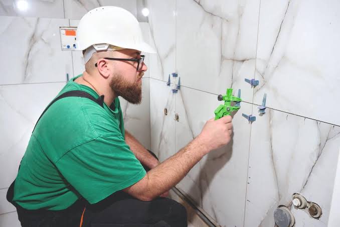 licensed bathroom contractors placing precision porcelain wall tiles.